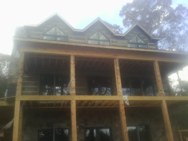 Dormers and porch framing on a large log home under construction — Roof Coating work by our crew in Eagle Bend