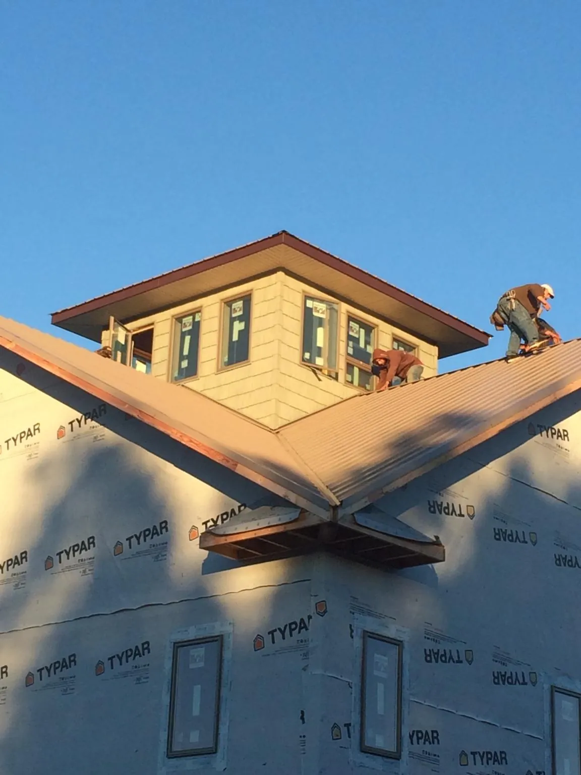 Roofers working around a rooftop cupola on a new metal roof at sunset — Roof Waterproofing in Eagle Bend by Roofing Brothers